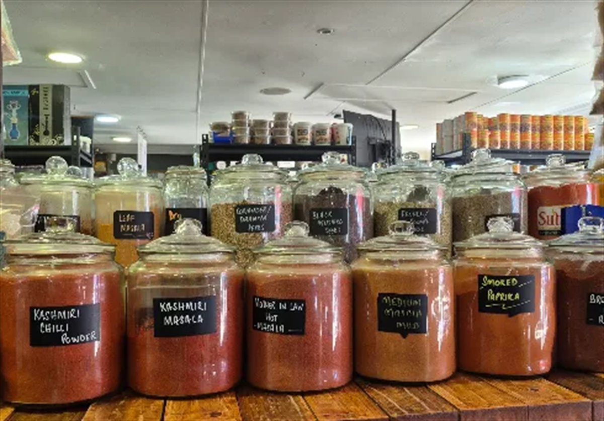Rows of large glass jars on the 4 Chilli counter, chalk-labelled Kashmiri Chilli Powder, Kashmiri Masala, Mother in Law Hot Masala, Medium Masala and Smoked Paprika